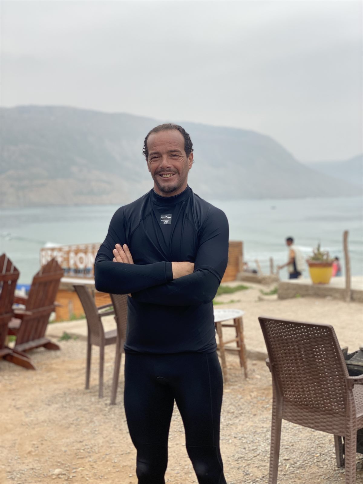 Local surf coach in wetsuit standing on the beach in Imsouane